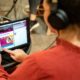 Frau mit Kopfhöhren vor Tablet, auf dem der Kommunen-Podcast abgespielt wird
